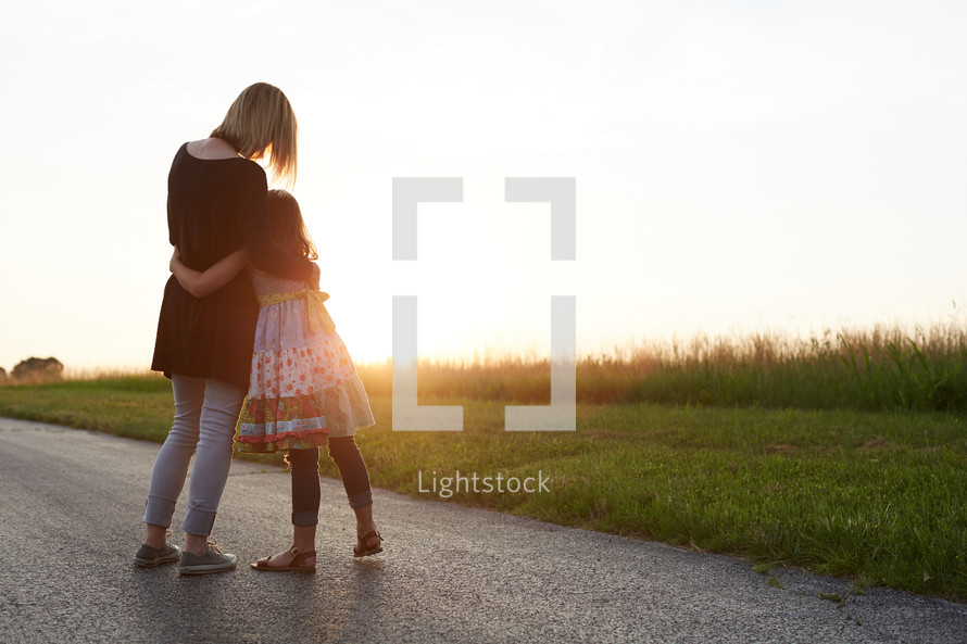 a mother and daughter hugging outdoors 