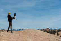 a man on a mountaintop holding a video camera 