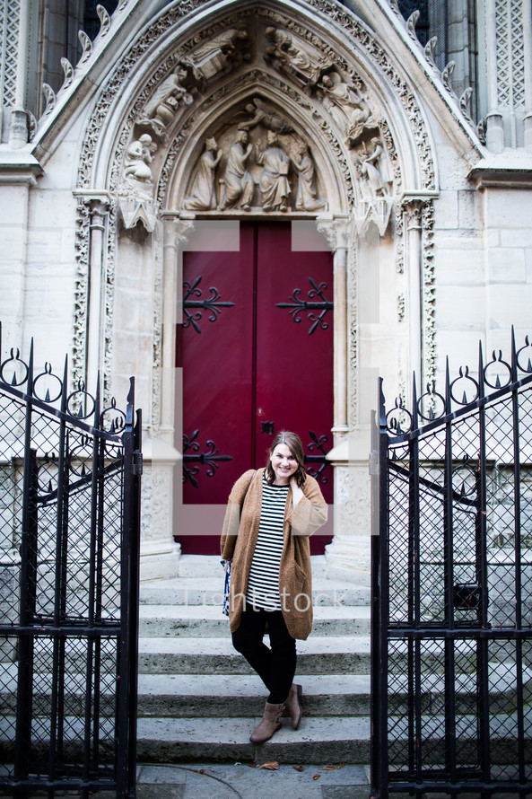 A woman posing in front of Cathedral doors in France 