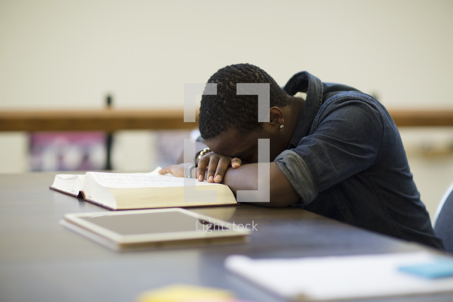 an exhausted man with his head on a book in a library 