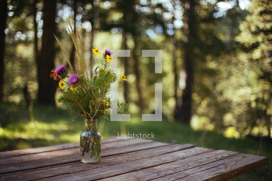 wildflowers in a vases on a picnic table 