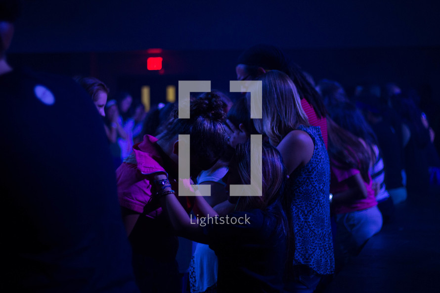 young praying over each other at a worship service 