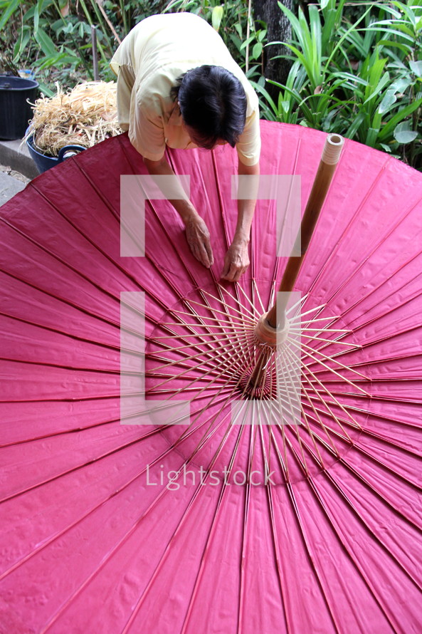 An Asian woman making a parasol 
