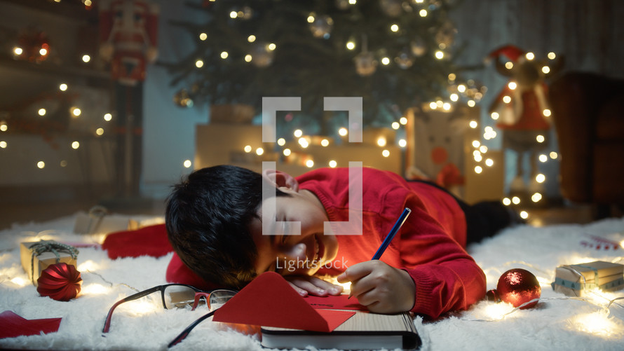 Child writing red letter for santa on the carpet