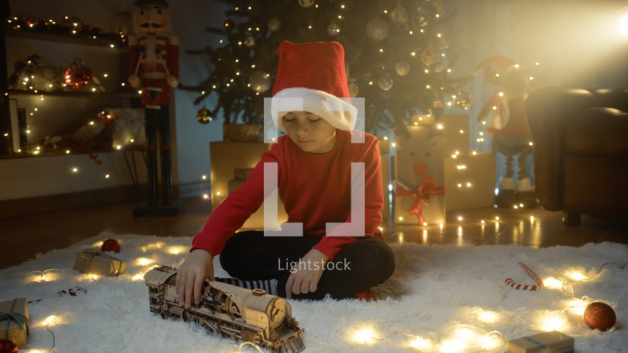 boy with Christmas hat playing with toy train