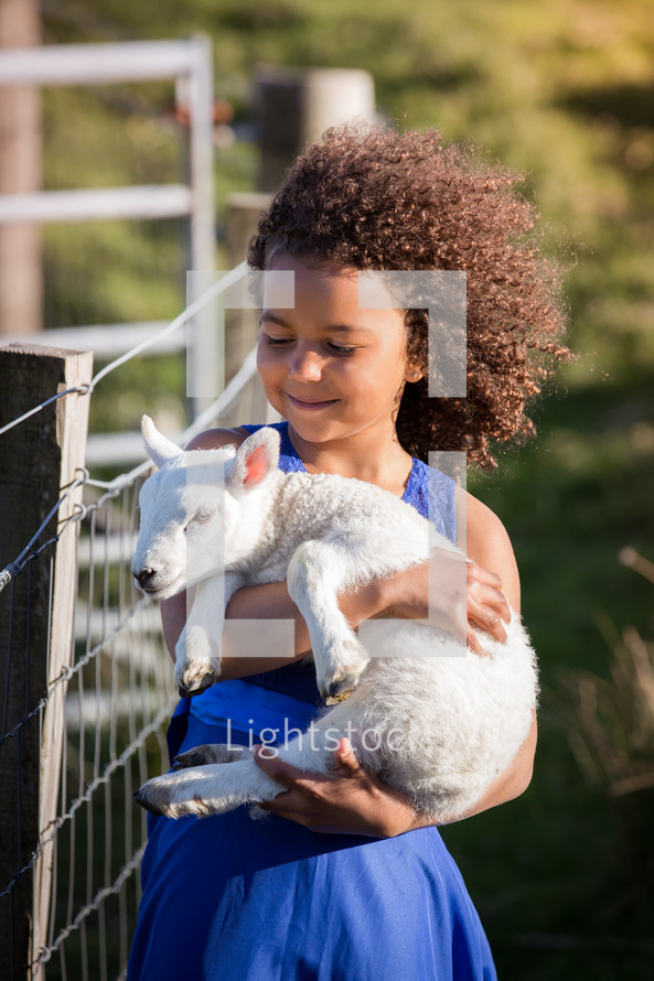 a girl holding a lamb 