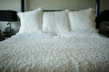 white bedding on a made bed 