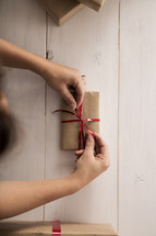 A woman tying a ribbon on a new gift.