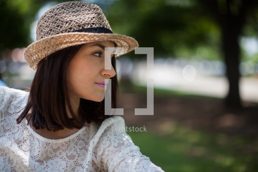 woman in a straw hat sitting outdoors 