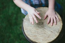 A child's hands playing a drum 