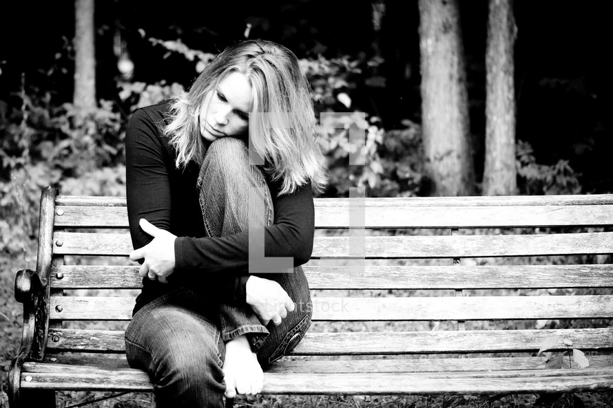 sad woman sitting on a park bench 