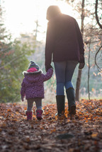 mother and toddler daughter walking in a forest 