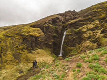 couple watching a waterfall on a green mountain 