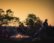 teens sitting around a fire pit 