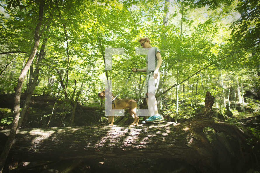 a man walking his dog on a leash in a forest 