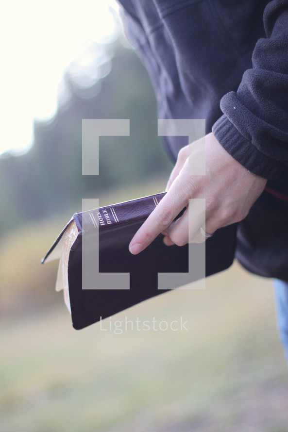 man holding a Bible outdoors 