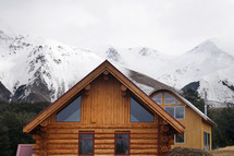 log cabin and snow capped mountain peaks 