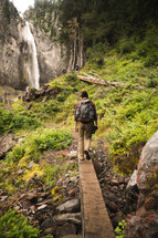 a man hiking in a forest near a waterfall 