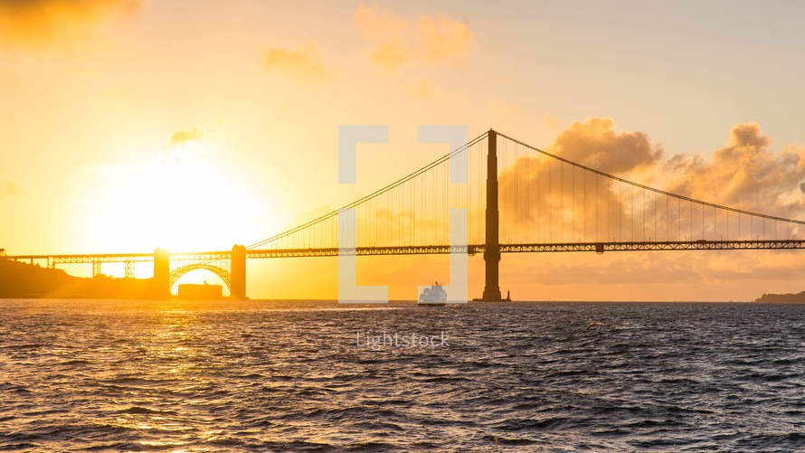 glow of sun at sunset and a bridge over water 