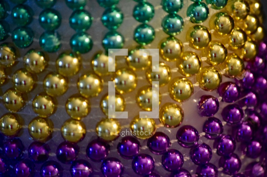 Festive Fat Tuesday beads in traditional Mardi Gras Purple, Gold, and, Green stripes 