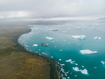 aerial view over icebergs floating in the ocean 
