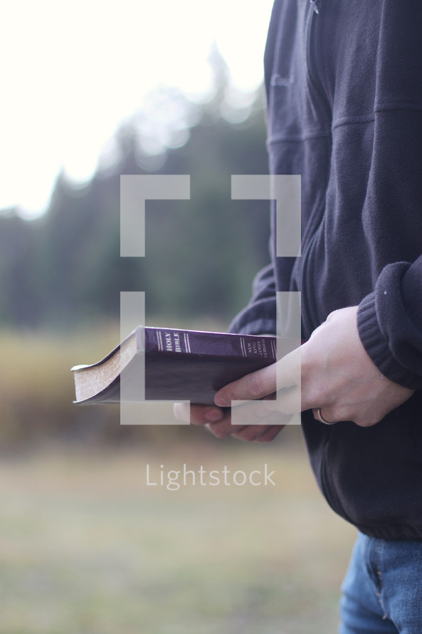 man carrying a Bible outdoors 