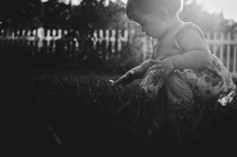 a toddler girl squatting in grass 