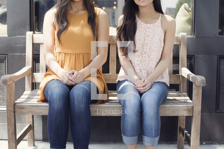 young women sitting on a park bench 
