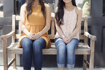 young women sitting on a park bench 