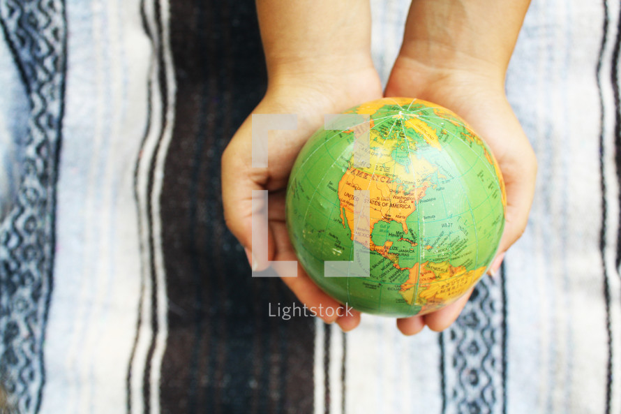 a young woman holding a globe in her hands 