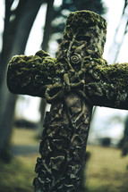old chiseled stone cross with moss