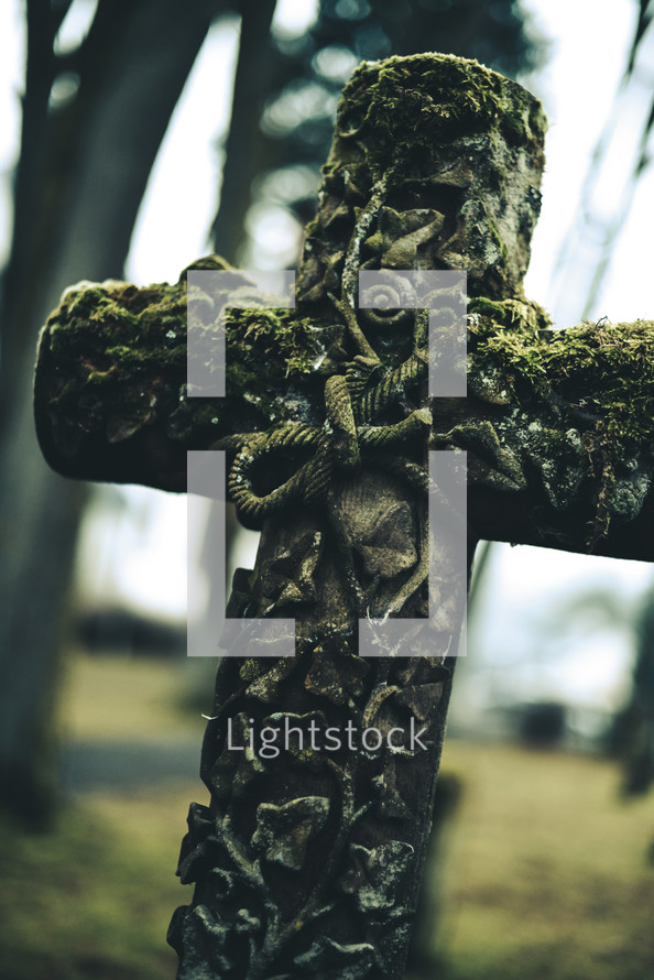 old chiseled stone cross with moss