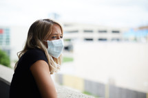 a young woman wearing a face mask looking over a railing 