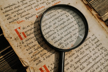 Researcher explores antique book with magnifier. Scientific translation of literature. Investigating manuscript with ancient writings