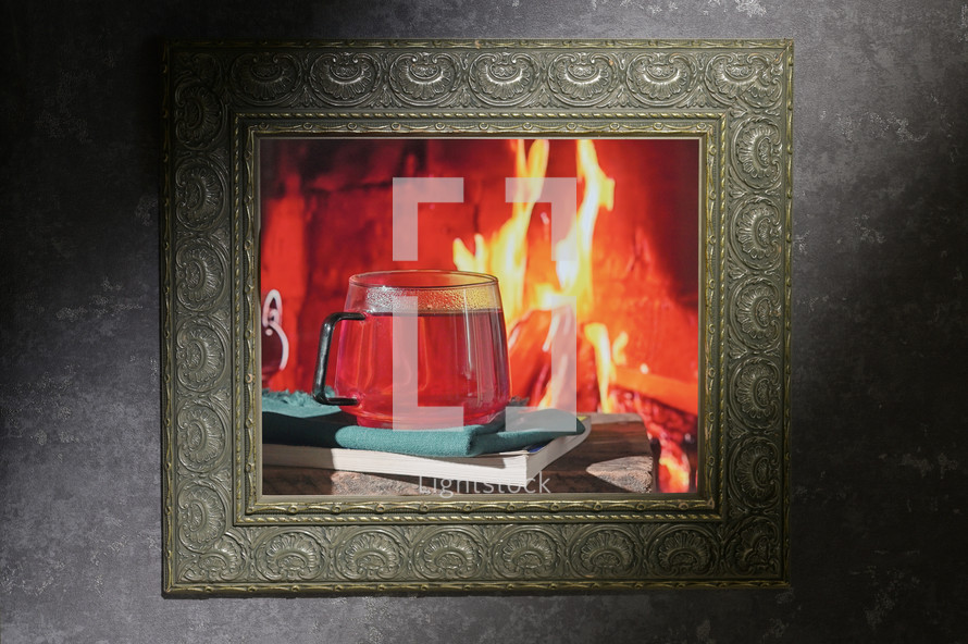 Glass mug with tea next to the fire in a frame