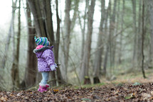 a little girl in a forest looking up 