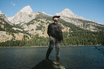 a man standing near a mountain lake 