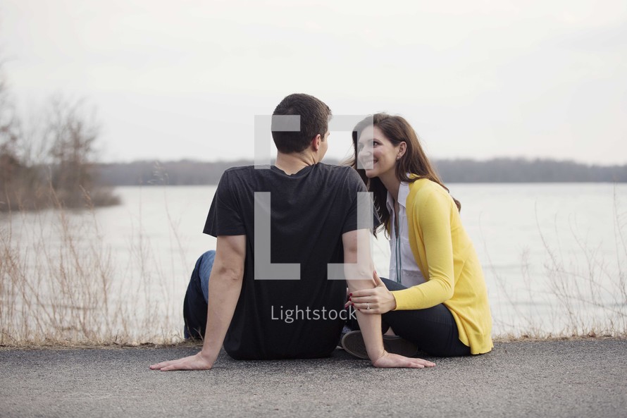 a couple sitting together and having a conversation by a lake 