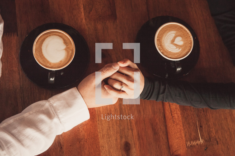 a couple holding hands over coffee 