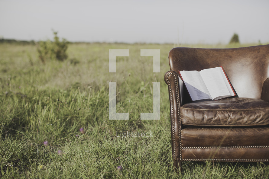 a Bible in a leather chiar in a field 