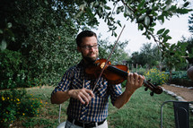 man playing a fiddle outdoors 