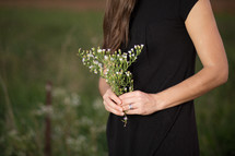 Woman in field holding bouquet of wild flowers