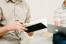 a man holding a journal and pen at a seminar 