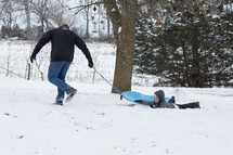 father and sons sledding in the snow 
