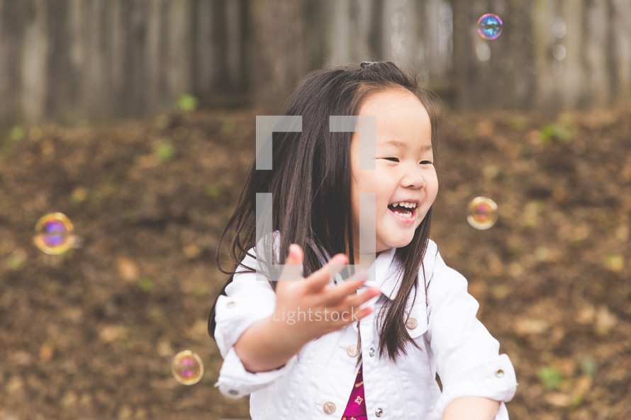 a girl child blowing bubbles 