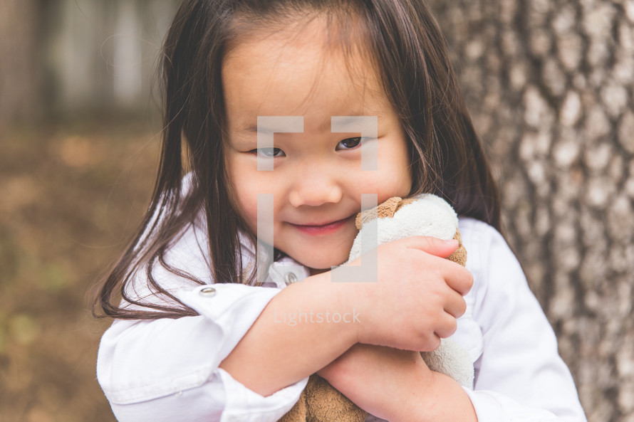 a girl child hugging her stuffed animal 