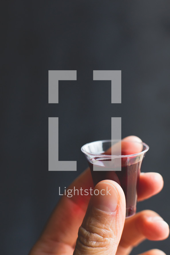 a hand holding a communion wine cup 