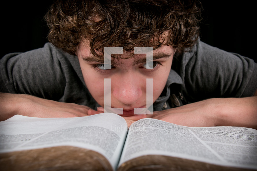 A teen boy reading a Bible.