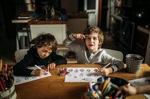 boys coloring on a coloring page at home 