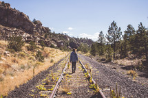 a woman walking down abandoned train tracks 